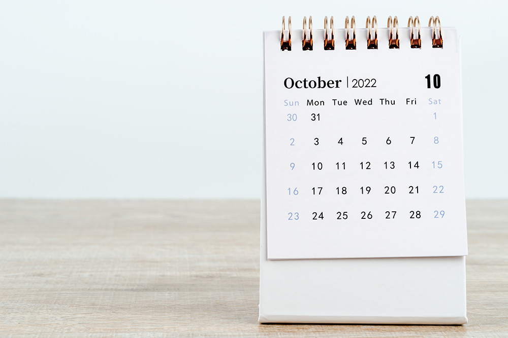 The October 2022 desk calendar on wooden background.