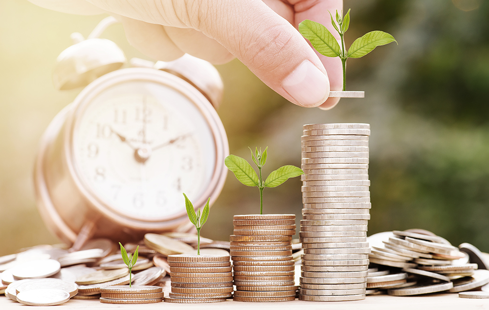 Close up of male hand stacking gold coins with green bokeh background ,Business Finance and Money concept,Save money for prepare in the future.Trees growing on coin