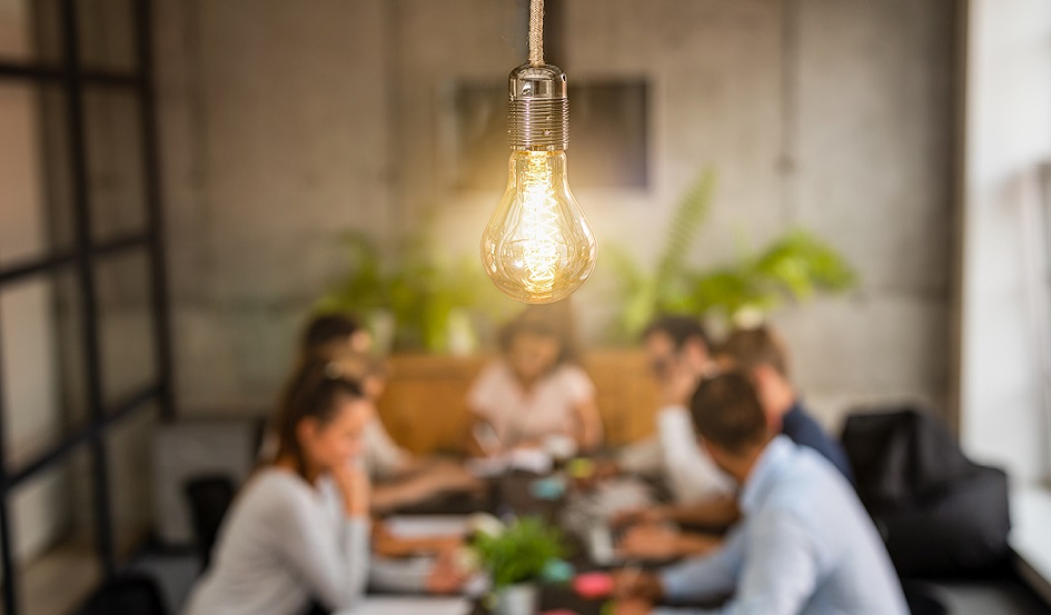 image shows lightbulb over meeting table