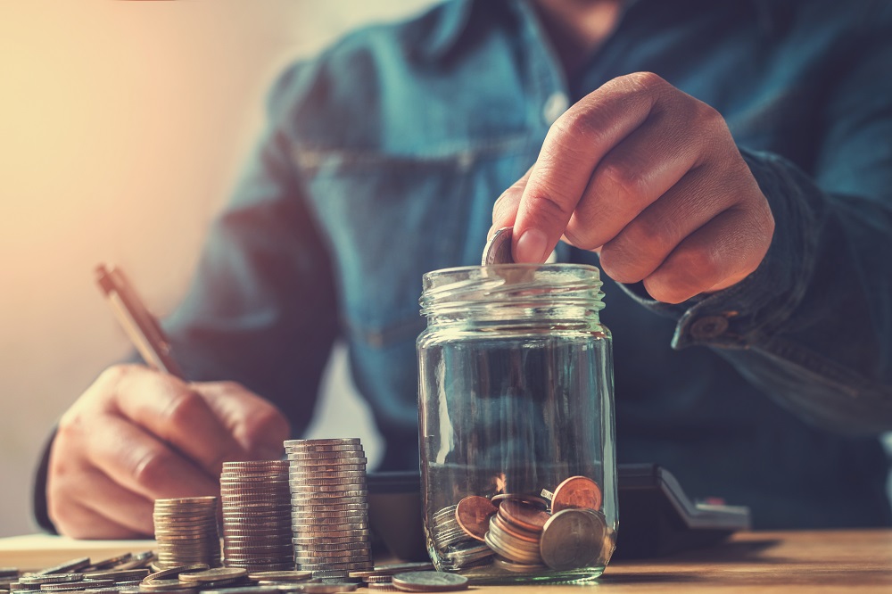 image of a person putting coins into a jar.