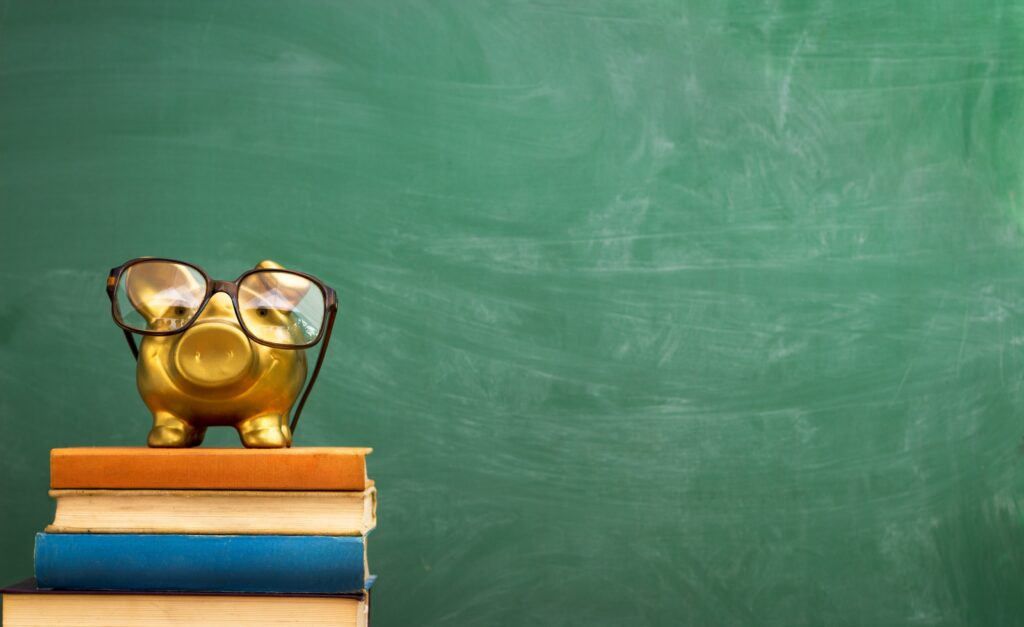 Piggy,Bank,With,Glasses,On,Books,,Education,Concept