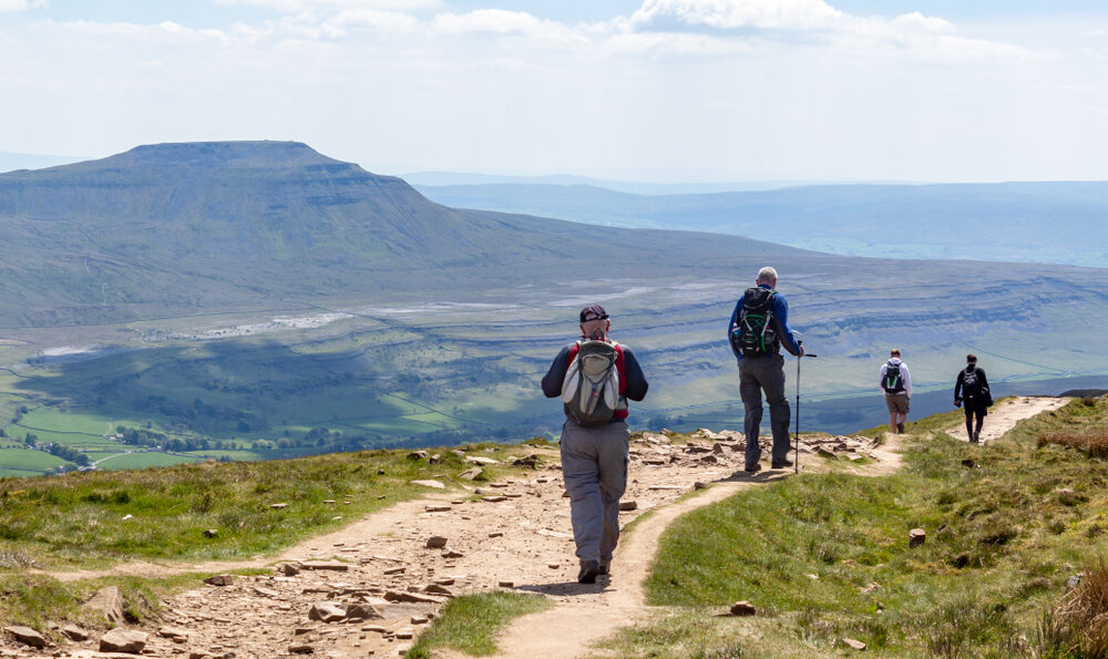 walkers on a path surrounded by mountains and beautiful scenery