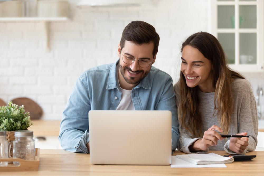 young couple looking at their computer and smiling.