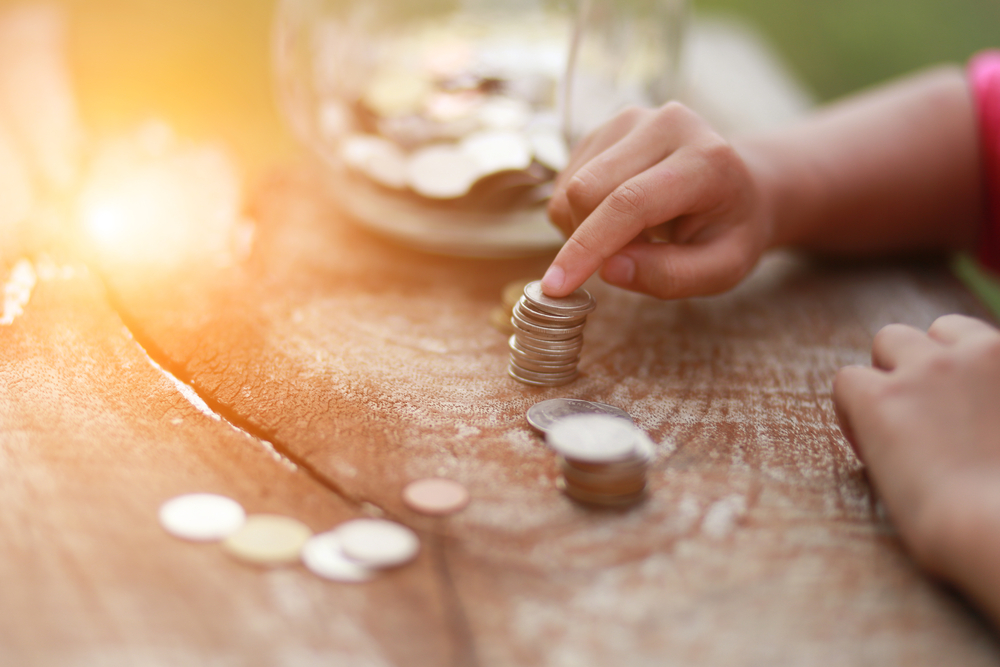 pile of coins with a hand resting on the top of the pile, indicating a stop.