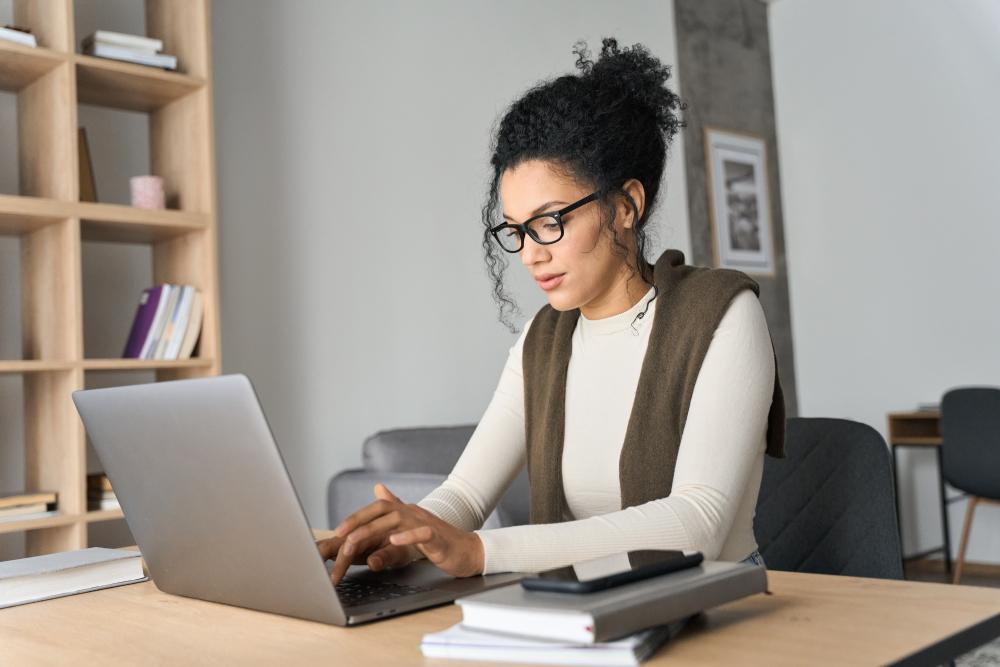 young girl sitting at her desk, working on a laptop