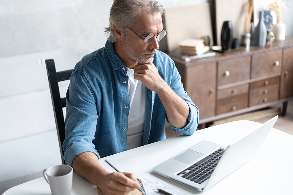 Middle-aged man working from home-office on laptop.