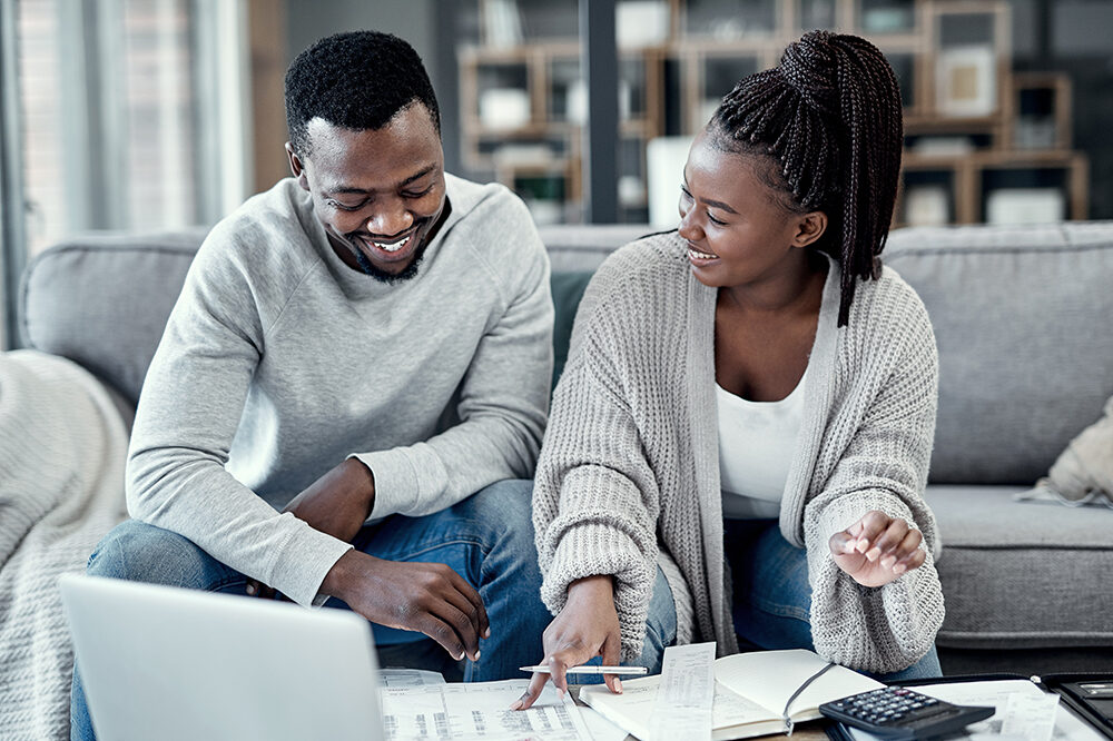 Finance, home budget and financial planning with a couple working on a laptop looking happy about savings, investment and mortgage insurance. Boyfriend and girlfriend calculating tax or future