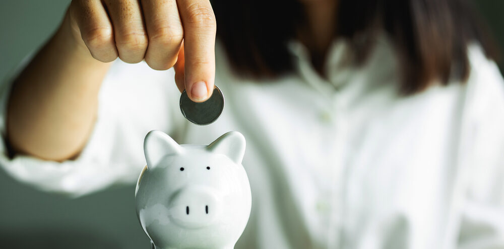 hand putting coin in piggy bank