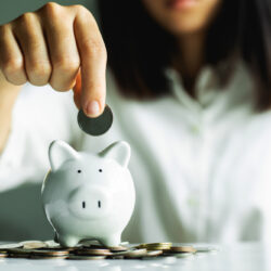 hand putting coin in piggy bank