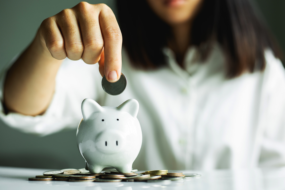 hand putting coin in piggy bank