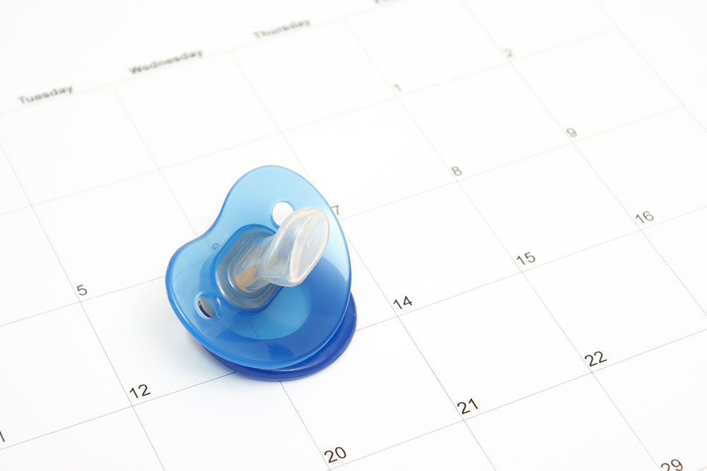 A babies pacifier on a calendar to conceptualize on many maternity ideas.