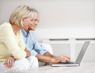 Portrait of a senior man with a woman working on a laptop at home